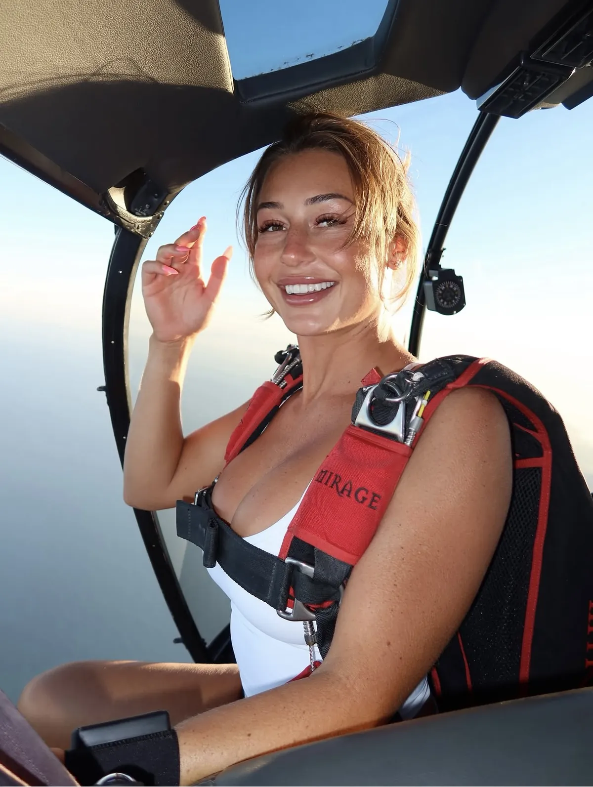 Jumper geared up in a Mirage rig sitting in the open door of a helicopter over the ocean
